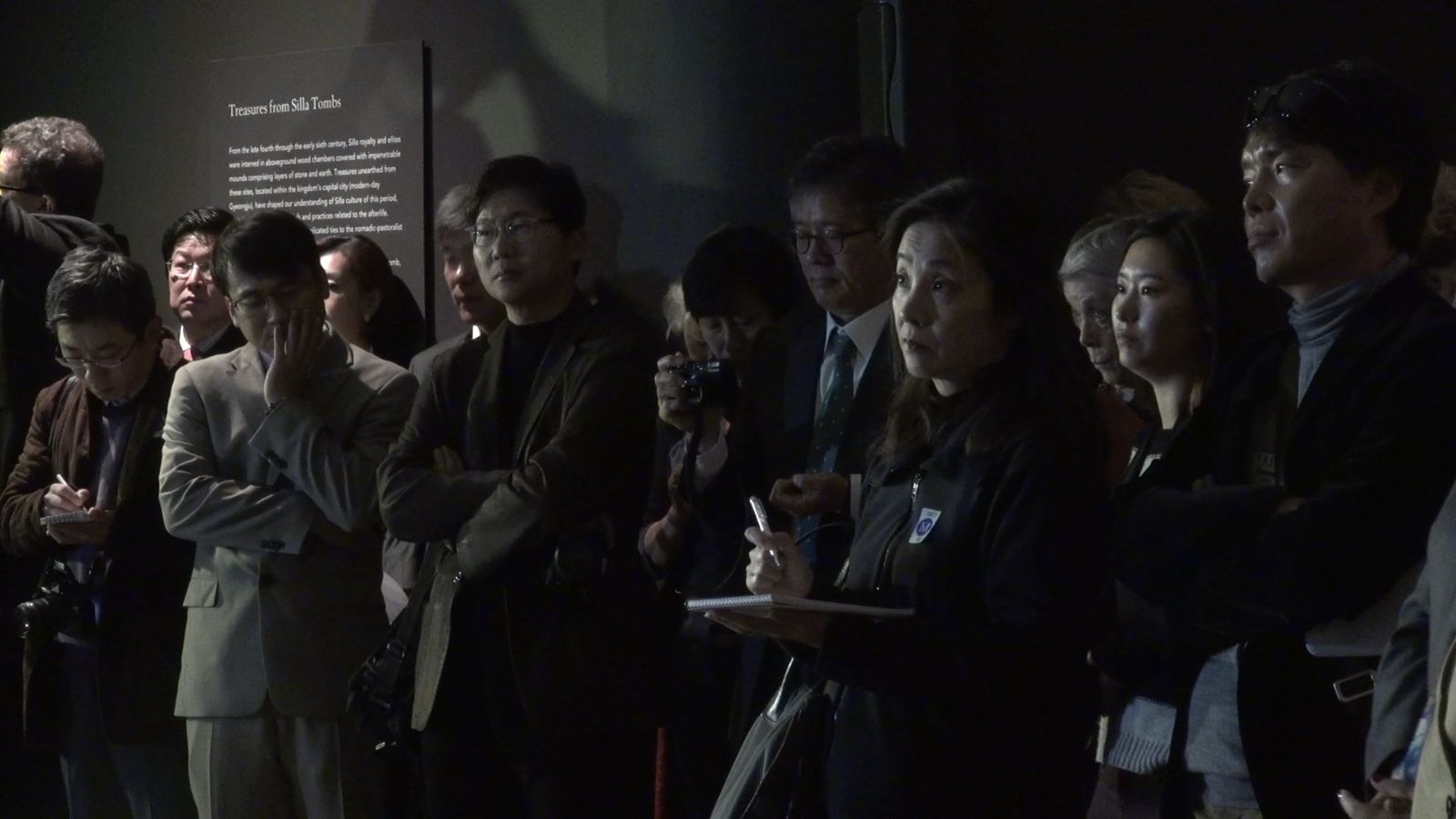 전시회를 관람하기 위해 모인 많은 관객들이 설명에 귀 기울이고 있다.