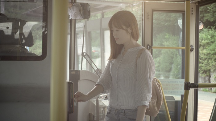 버스에 탄 승객이 카드를 찍어 요금을 결제하고 있다.
