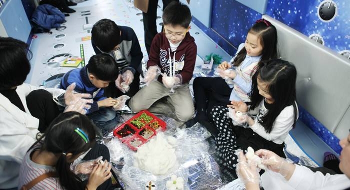 ‘움직이는 예술정거장’의 문화예술교육 프로그램에 참여한 아이들이 옹기종기 모여 앉아 떡만들기체험을 하고 있다. (사진제공: 문화체육관광부)