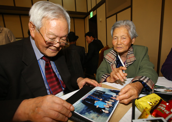 20일 열린 남북 이산가족 상봉행사에서 사촌간인 남측 강정구(81) 할아버지와 북측 강영숙(82) 할머니가 가족사진을 함께 보고 있다.
