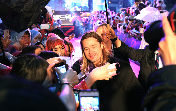 브래드 피트가 11일 레드카펫 행사를 찾은 팬들과 함께 사진을 찍으며 웃고 있다. (사진: 전한)