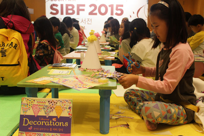 서울국제도서전의 아동관 책예술공방에서 오감발달 액티비티북 체험 프로그램에 참가한 어린이들이 다양한 종이 모형을 만들고 있다.