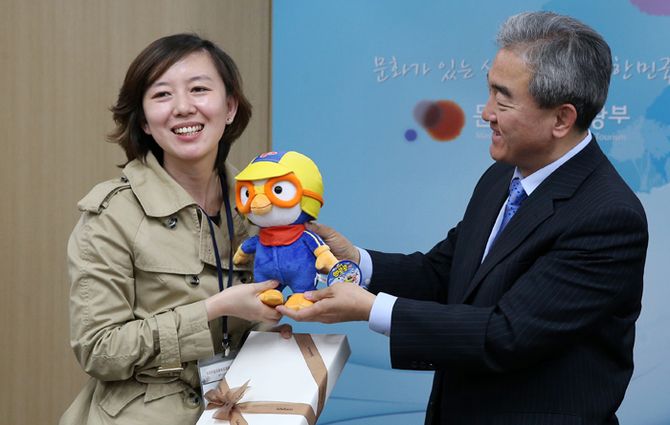 문화체육관광부 유진룡 장관으로부터 화장품과 뽀로로 인형을 선물받은 중국교육보의 리우 친(Liu Qin) 기자가 환하게 웃고 있다. 전한 기자