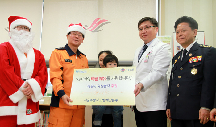 소방관계자들이 지난 24일 몸짱 소방관 달력 프로젝트로 모인 기부금 500만원을 서울 한강성심병원에서 화상 치료를 받고 있는 신재빈군에게 전달하고 있다.