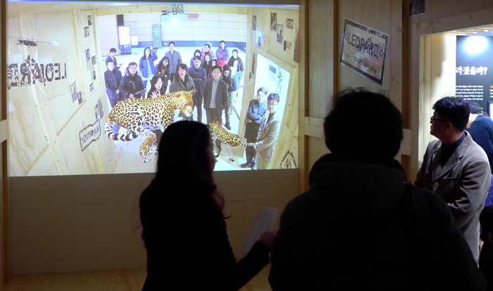 전시회 ‘잊혀진 이름, 한국표범’에 온 관람객들이 대형 스크린 안에서 3D그래픽으로 구현한 한국표범을 가상으로 만나보는 체험을 하고 있다.