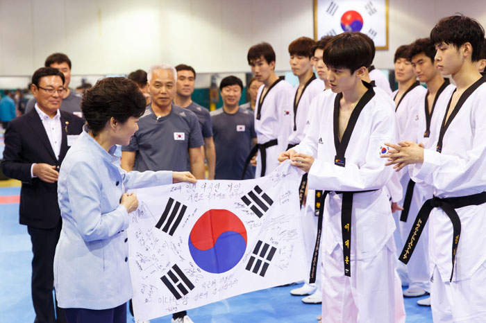  박근혜 대통령(왼쪽)이 2014 인천 아시안게임 개막을 앞둔 25일 서울 노원구 태릉선수촌을 방문해 태권도 국가대표팀 이대훈선수로부터 선수들의 다짐이 담긴 태극기를 선물받고 있다. (사진: 청와대)