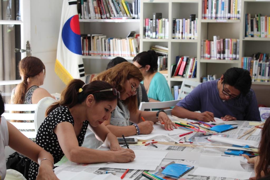 워크숍 참가자들이 진지한 표정으로 연 종이에 그림을 그리고 색을 칠하고 있다.