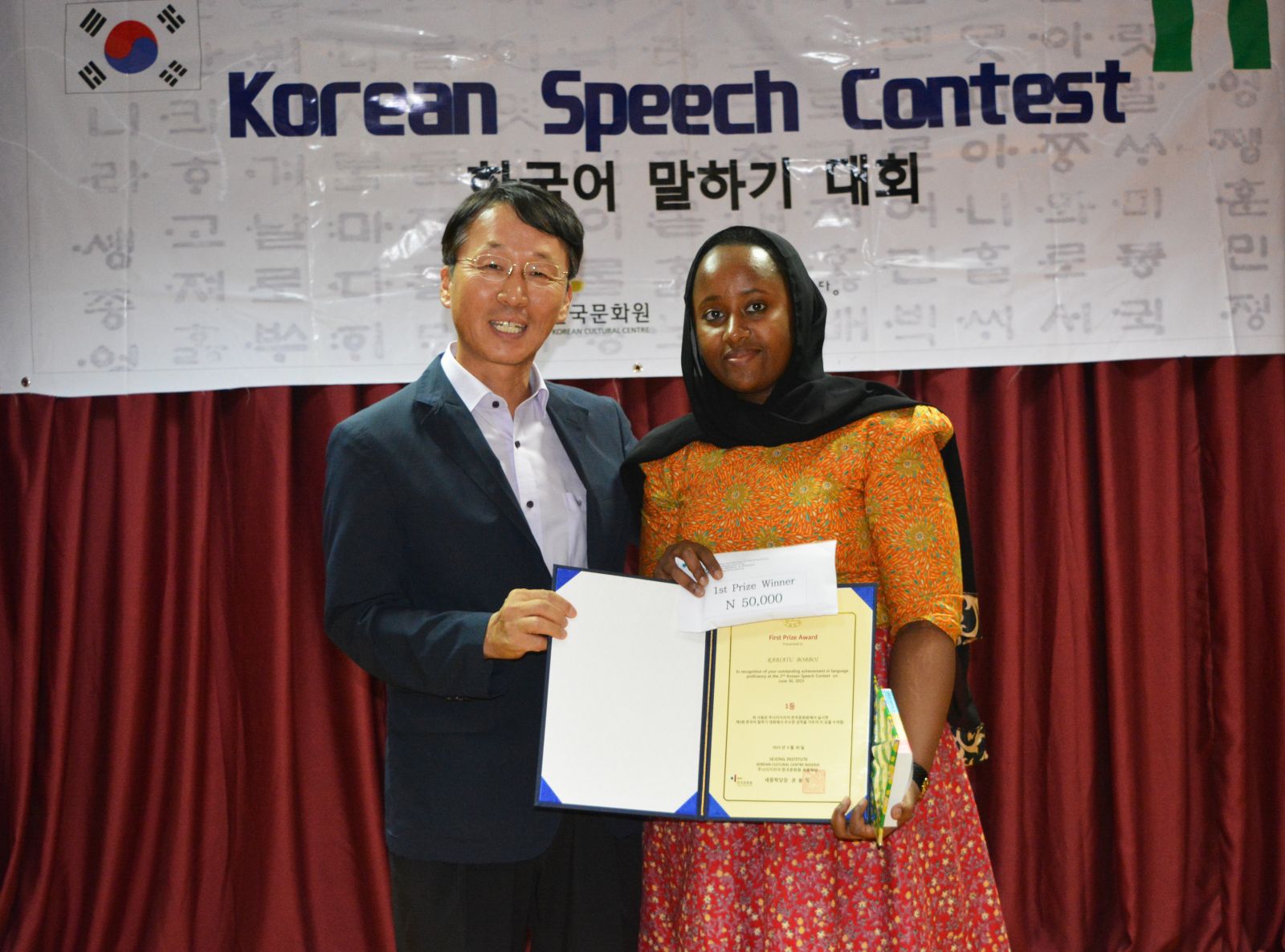 &lsquo;왜 부산을 좋아해요?&rsquo;란 주제로 이번 한국어 말하기 대회에서 최우수상을 차지한 Rabiatu Bobboi이 주나이지리아 문화원 권용익 원장과 기념 사진을 찍고 있다.