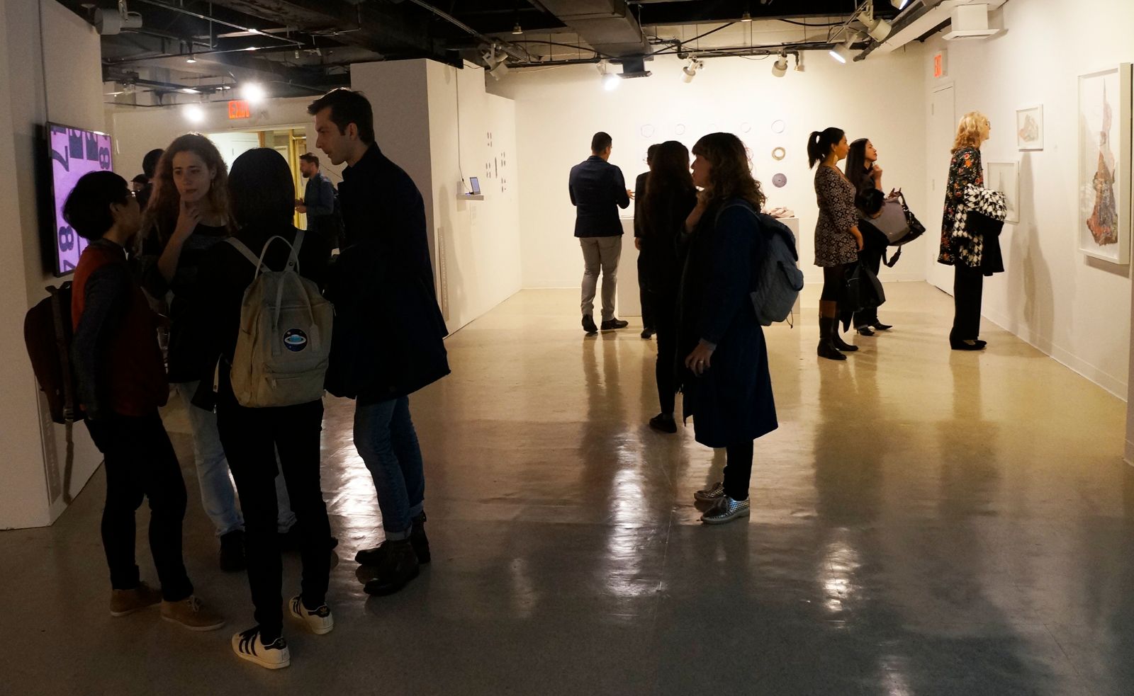 좌측 이동 벽에 걸려 있는 린 킴의 애니메이션 작품 앞에서 작가가 다른 작가와 지인들에게 본인 작품에 대해서 설명하고 있으며, 뒤편에 많은 관람객들이 작품을 감상하고 있다.