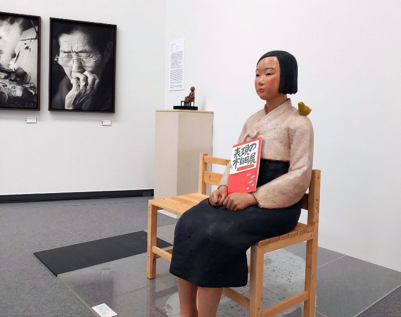 ▲ 일본 아이치현 나고야시에서 열리고 있는 일본 국제예술제 ‘아이치 트리엔날레 2019’에 출품된 ‘평화의 소녀상’에 '표현의 부자유전’ 팸플릿이 들려있다. 연합뉴스
