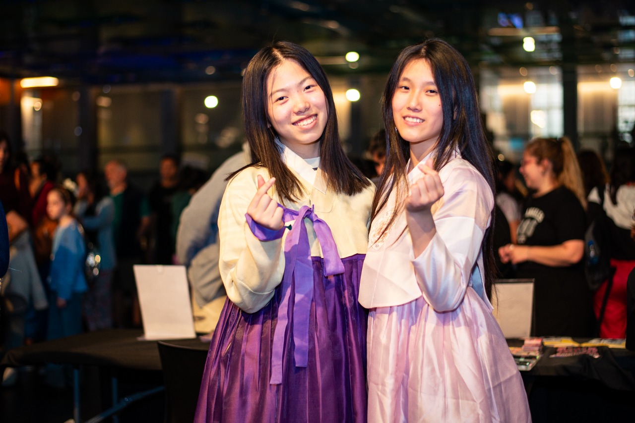 한복을 입고 손하트를 하며 정면을 보고있는 두 여자