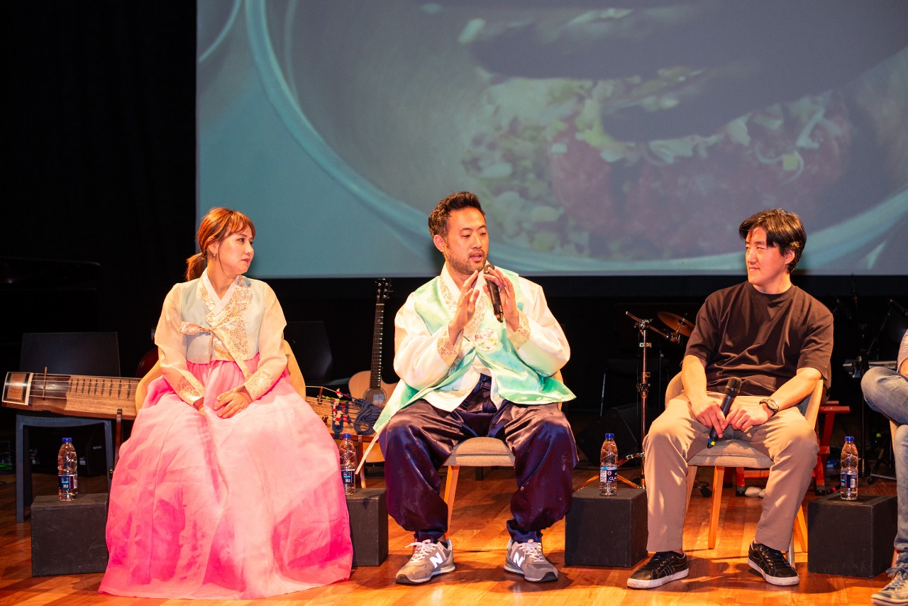 한복을 입은 두사람과, 한 사람이 앉아있다